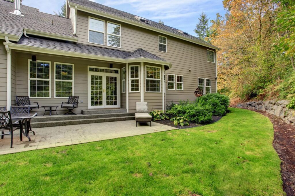 Backyard view of home with green lawn and patio