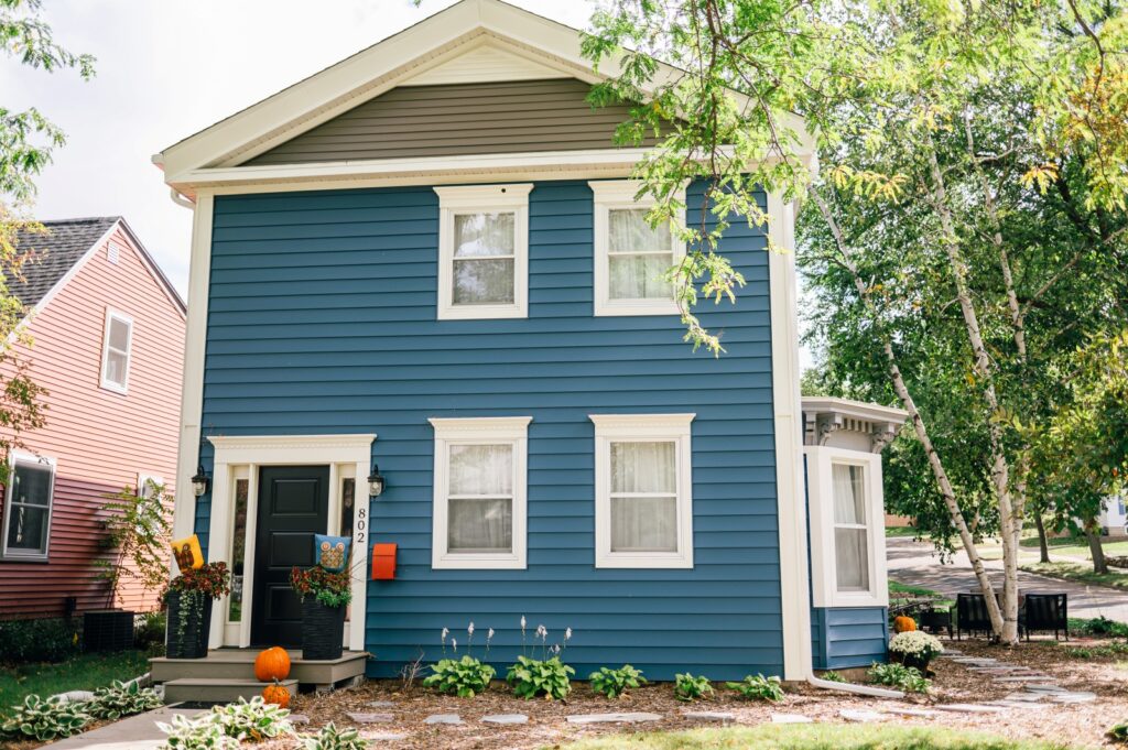 Two-story blue home with white trim and landscaped yard
