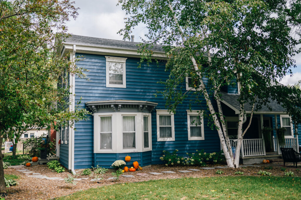 Two-story blue home with white trim and landscaped yard