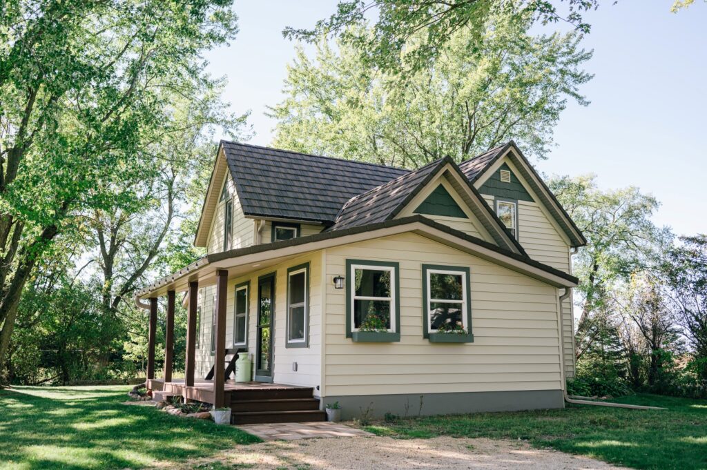 Single-story home with light siding and dark trim surrounded by trees