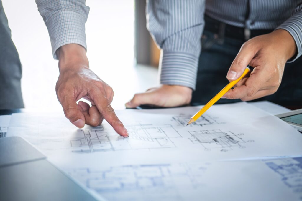 Close-up of several male hands of a planning team looking at a blueprint